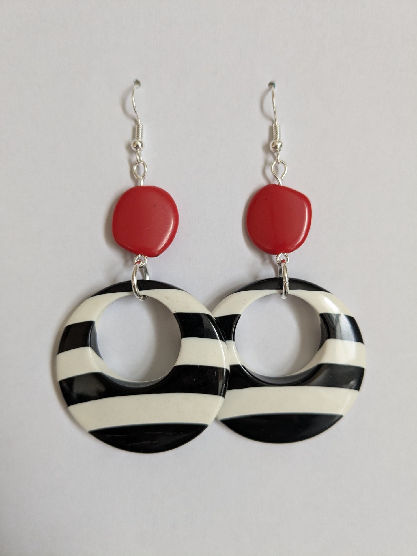 Bold and fun 1960s style dangle earrings, made from plastic black and white striped hoops and a red plastic bead, with new silver-plated wires.