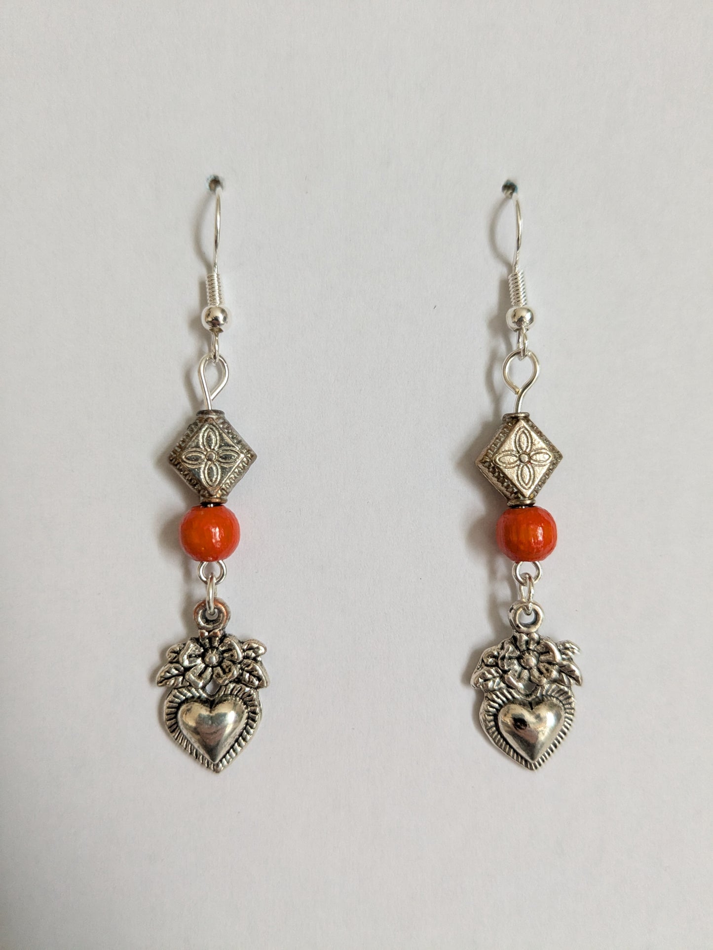 Dangle earrings made with silver tone vintage heart charms and red wooden beads, with new silver-plated wires.