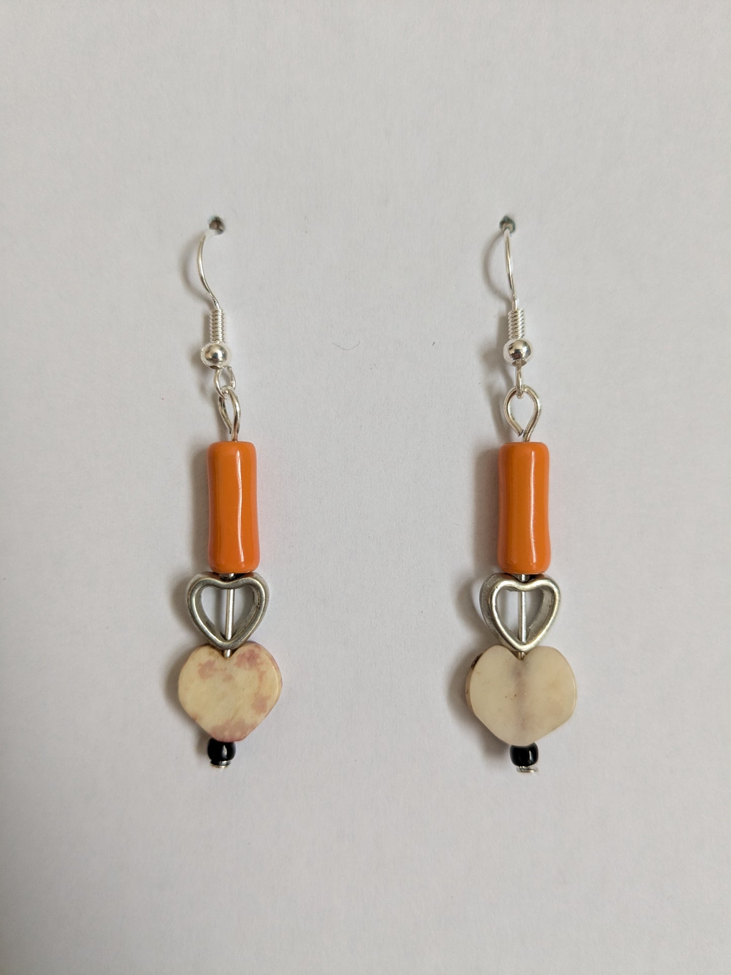 Dangle earrings made from two vintage heart beads and an orange ceramic bead, with new silver-plated wires.
