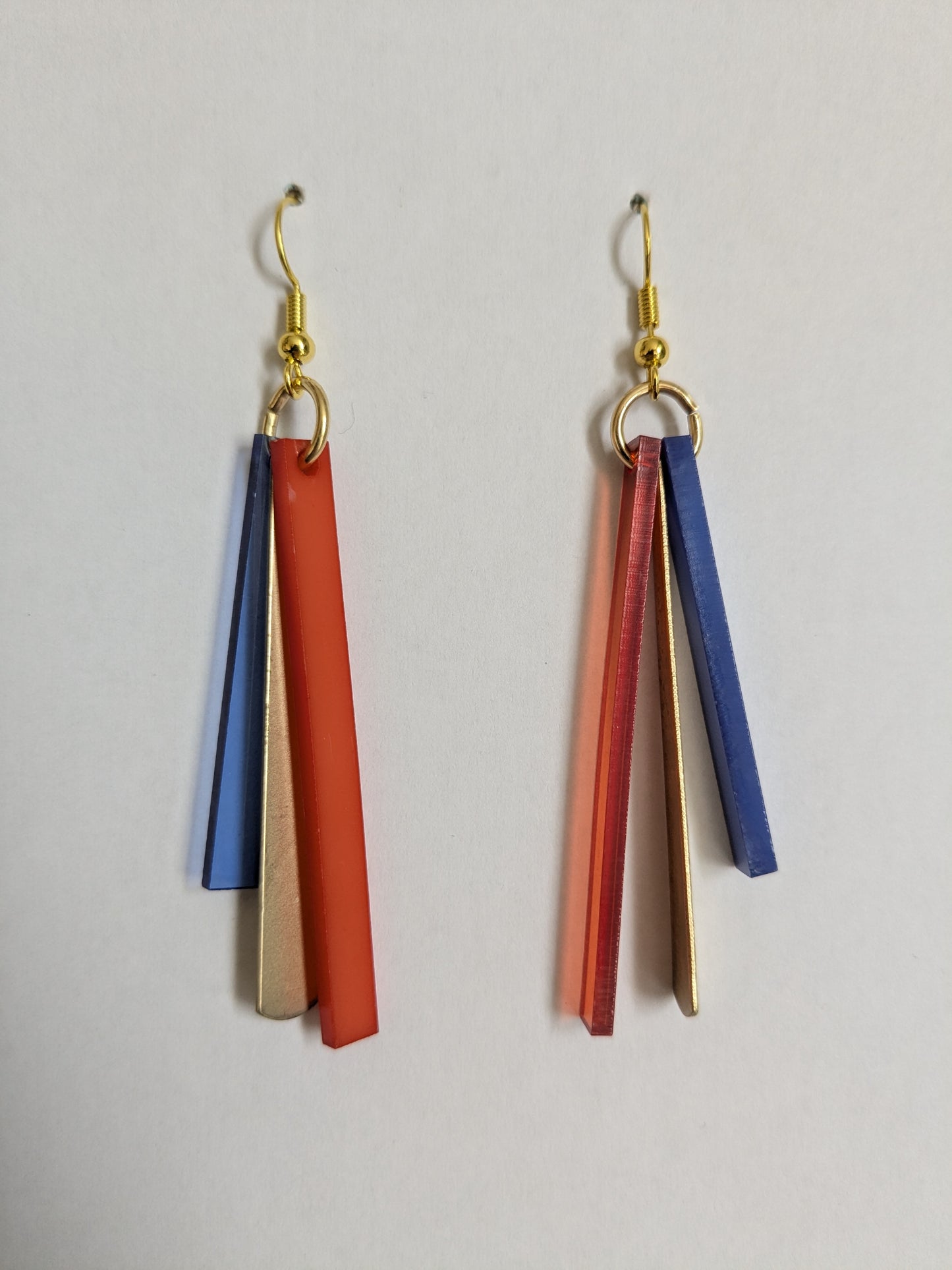 Colourful dangle earrings made from orange and blue acrylic and brass bars, with new gold-plated wires. 