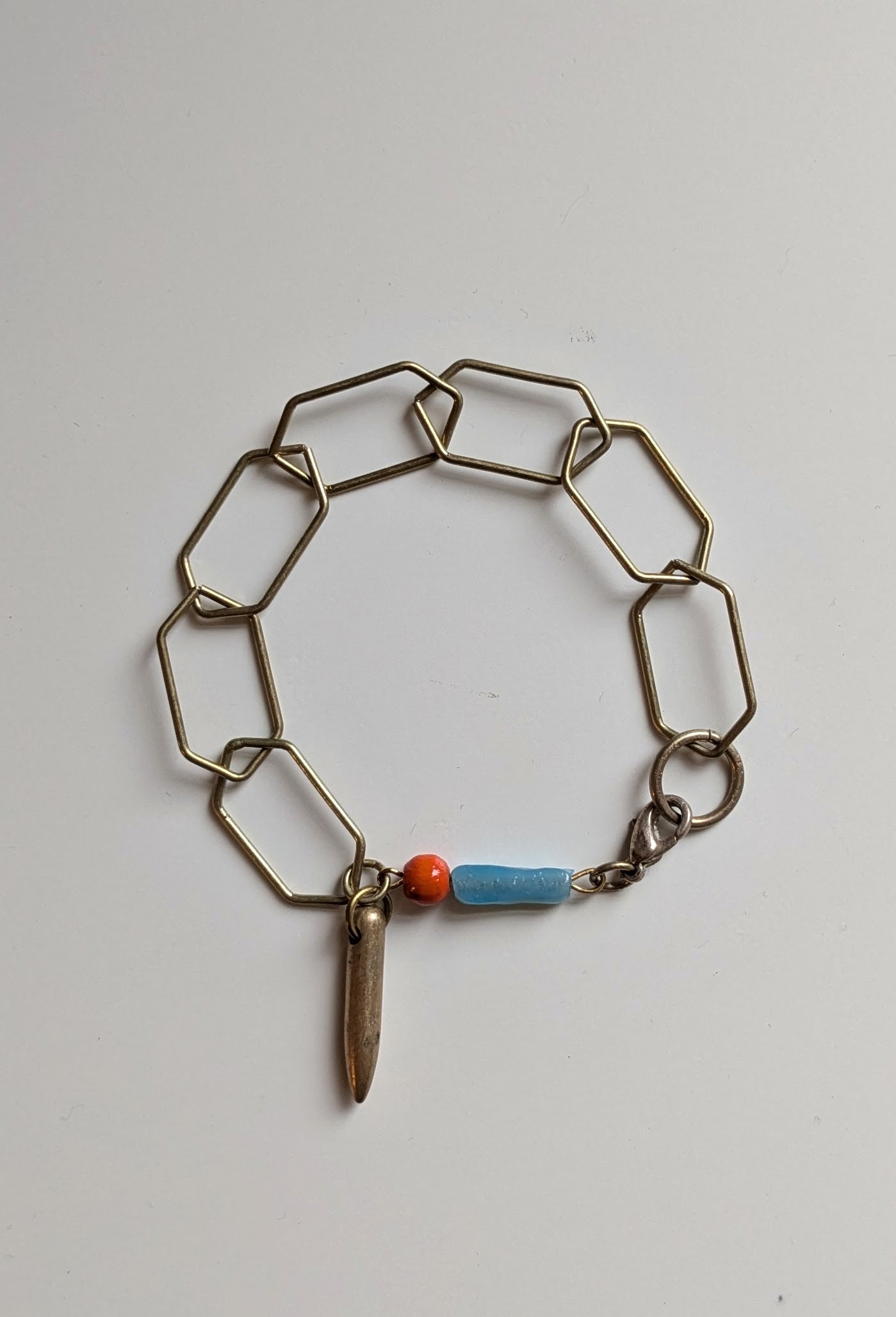 Lightweight bracelet made from geometric brass links, a blue vintage bead, a red wooden bead and a brass bullet charm. Great everyday bracelet.