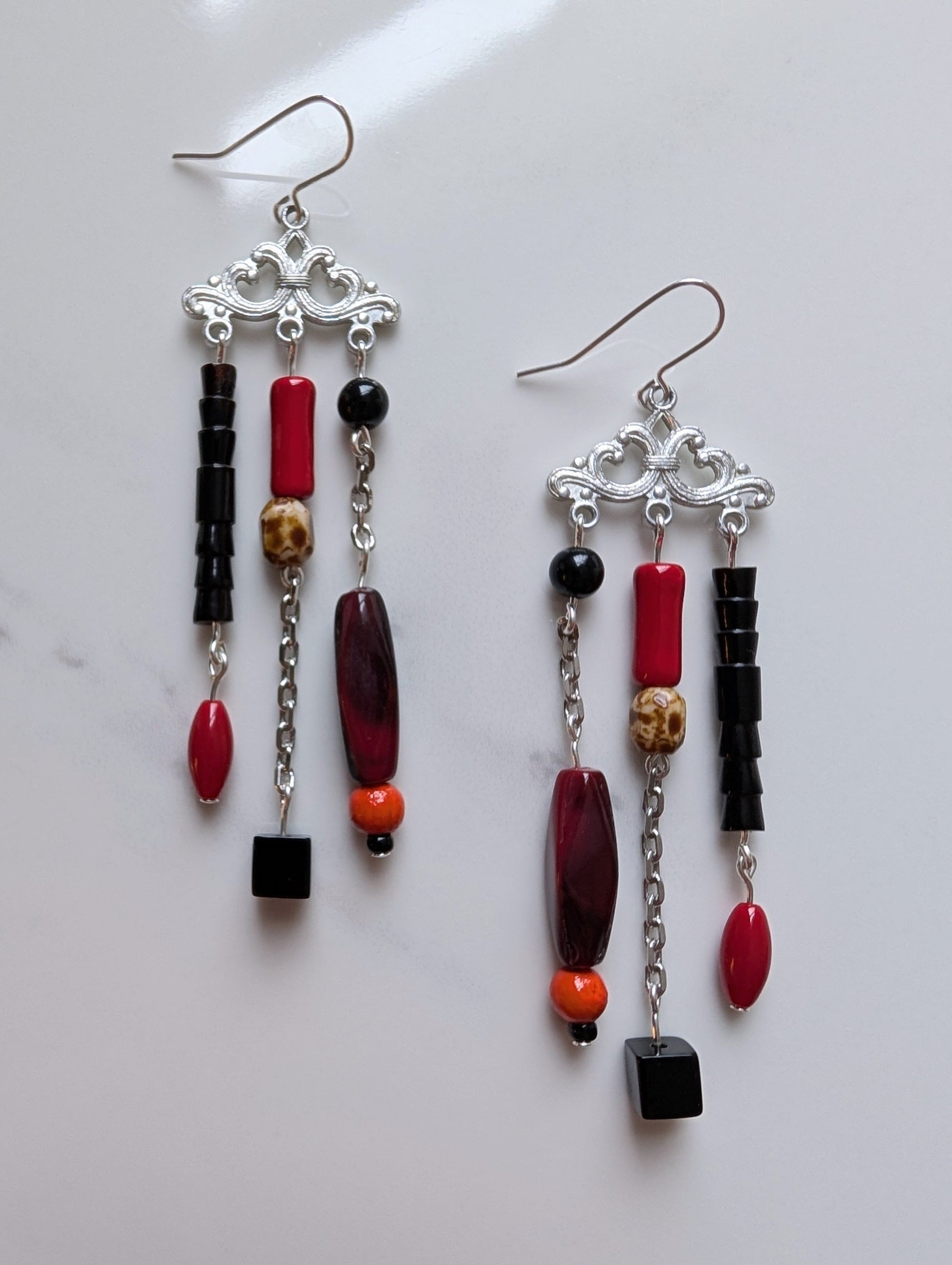 Pair of beaded earrings with red, black, and orange beads on a white background